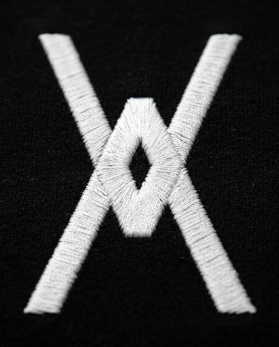 Close up of the Over You logo embroidered in white thread on a black tee